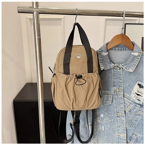 Detail of khaki nylon travel backpack with black drawstring pocket and metal logo