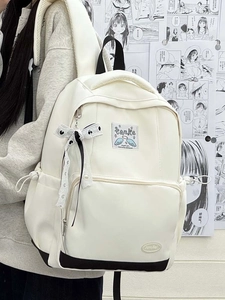 Detail showing cream canvas backpack with polka dot ribbon bow and contrast black trim
