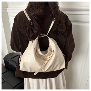 Detail of cream multi-way faux leather tote bag worn by a model in a minimalist setting
