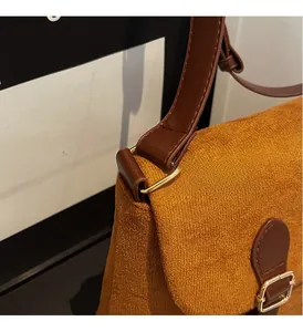 Detail of caramel suede texture, dark brown leather strap, and polished gold hardware