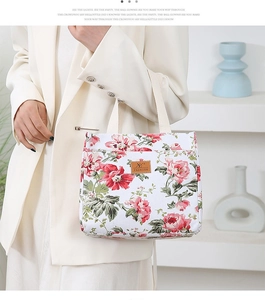 Detailed shot of floral canvas lunch bag featuring red flowers and woven handles