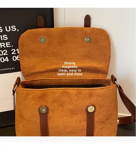 Detail view of the strong magnetic closure on the brown suede shoulder bag