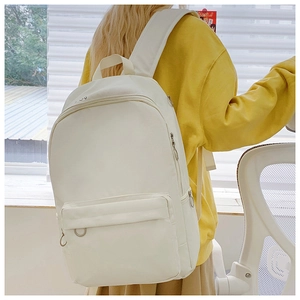 Detail shot of ivory canvas backpack side pocket and durable fabric on a yellow hoodie
