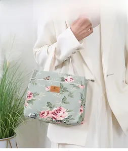 Close-up of light green canvas tote bag featuring vintage rose prints and leather label