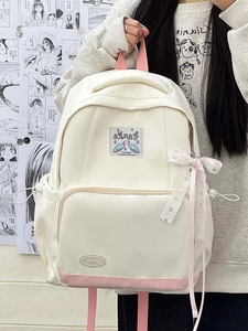 Detail of cream school backpack with pink straps and cute angel wing logo patch