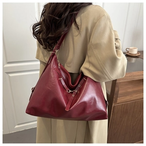 Detailed view of vintage burgundy leather tote bag styled with a beige trench coat