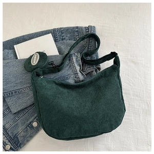 Close-up of dark green corduroy hobo bag with adjustable strap and mini round pouch charm