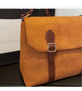 Close-up of caramel suede handbag showing soft texture and brown leather strap detail