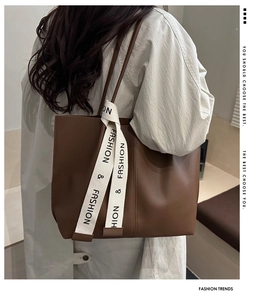 Detail view of large brown faux leather tote bag with fashion printed strap on a model