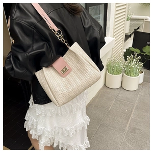 Detail of woven straw tote bag with pink leather trim and golden metal twist lock closure