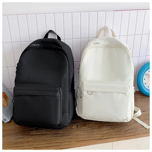 Close-up of black and beige canvas backpacks with star icons on a wooden surface