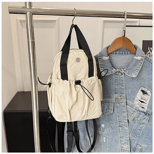 Close-up of beige nylon backpack with drawstring pocket and metallic logo detail