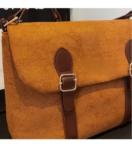 Detail of the brown suede shoulder bag featuring a glossy gold clasp and leather strap