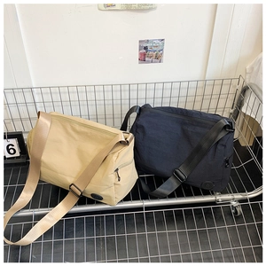 Detail of large nylon messenger bags in khaki and navy with adjustable wide straps