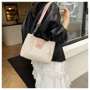 Detail of cream woven tote bag with pink leather flap and gold chain on a model