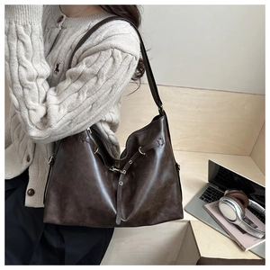 Model wearing dark brown vintage leather tote bag with retro gold hardware in cozy cafe