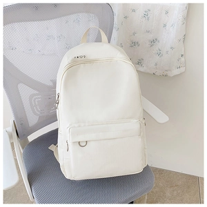 Detail view of white canvas backpack featuring decorative symbols and metal ring zipper