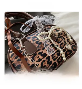 Detail of leopard print handbag with pearl chain, cherry charm and lace bow accents