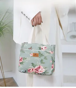 Detail of green floral canvas bucket bag featuring a leather logo and white woven handles