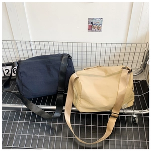 Detail of large capacity nylon crossbody bags in black and khaki with adjustable straps