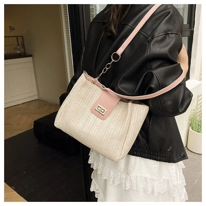 Close-up of beige woven tote bag featuring pink leather trim and golden metal swivel lock