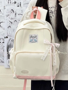 Detail of a beige canvas backpack with pink accents and a decorative checkered ribbon