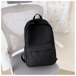 Close-up of a black minimalist backpack featuring dual zippers and front pocket on a chair