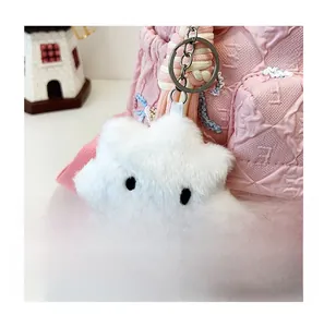 Close-up of a plush white cloud charm with a smiling face on a pink striped backpack