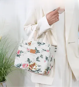 Close-up of floral canvas tote bag featuring pink rose patterns and a leather brand label