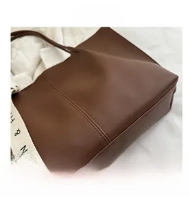 Detail of dark brown tote bag showing smooth PU leather texture and vertical stitching