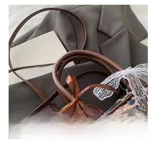 Close-up of leopard print handbag with pearl charm, lace trim and brown ribbon bow