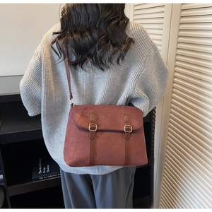 Detail view of the vintage suede crossbody bag with leather straps and metal buckles