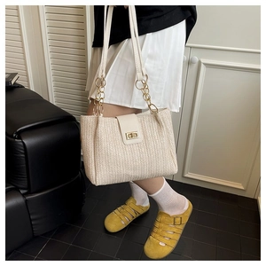Detail of woven beach tote with white leather flap and golden twist-lock closure