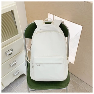 Detail of white nylon backpack featuring minimalist weather icons on a green corduroy chair