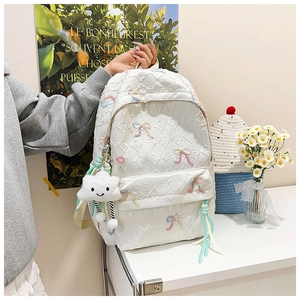 Detail of white quilted backpack with colorful bow embroidery and a cute cloud charm