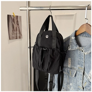Detail of black mini nylon backpack with drawstring pocket and sturdy dual top handles