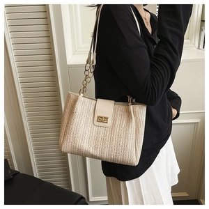 Detail view of woven herringbone pattern and gold chain strap on beige tote bag