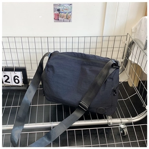 Macro view of a black nylon crossbody bag with zipper details in a metal cart