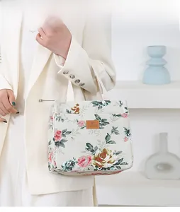 Close-up of canvas bucket bag featuring red rose floral prints and brown leather logo tag