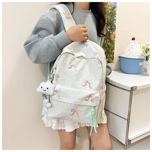 Detailed view of white quilted backpack with colorful bow embroidery and soft cloud pendant