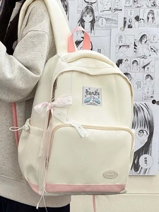 Detail view of cream school backpack with pink ribbons and branding on side pocket