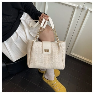 Close-up of cream woven tote bag featuring golden chain handle and metallic square buckle