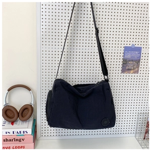 Detail of black nylon bucket bag featuring a side zipper pocket and circular logo patch