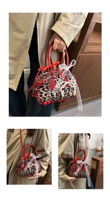 Detail showing leopard print Boston bag with red leather handles and cherry pearl charms