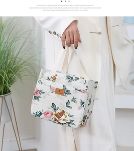 Detailed view of the rose floral print on a cream canvas bucket bag with leather brand logo