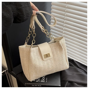 Close-up of woven straw tote bag with cream leather flap and golden twist lock
