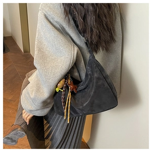 Detail of black suede crescent bag with colorful woven rope and star pendant charm