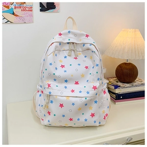 Close-up of white canvas backpack with colorful star print and soft rope zipper detail