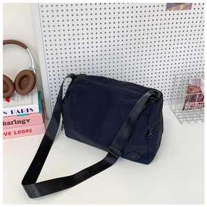 Close-up of black nylon bucket bag with adjustable wide strap and round logo detail