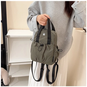 Detail of army green nylon backpack with silver M logo and drawstring pocket